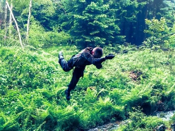 Person schwingt an Seil über das Gelände beim Survival Training