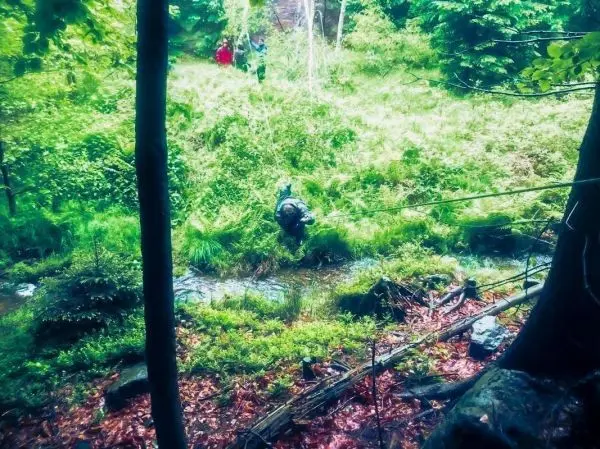 Person überquert einen kleinen Bach mit einer Seilquerung