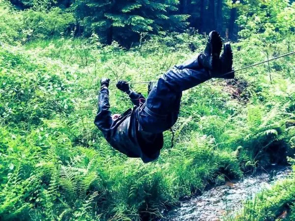 Selbstgebaute Seilquerung über einen kleinen Bach mit einer Person in Sicherheitsausrüstung