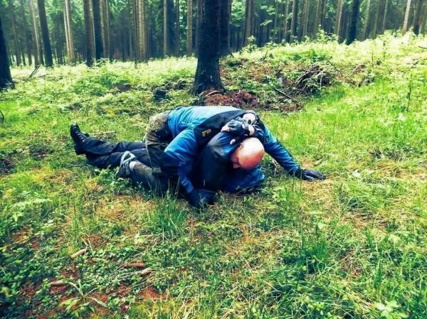 Zwei Personen liegen auf dem Boden im Wald und üben eine Technik