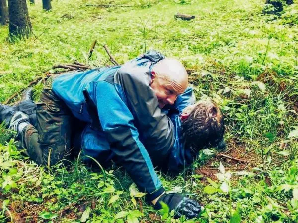 Zwei Personen liegen im Gras und führen eine körperliche Auseinandersetzung durch