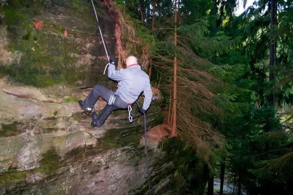 Abseilen an einer Felswand mit Sicherungsseil und Karabiner