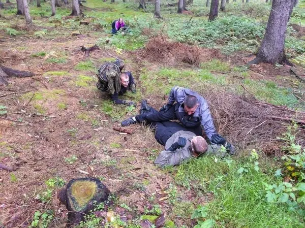 Drei Personen im Wald führen eine Übung zur Personenrettung durch