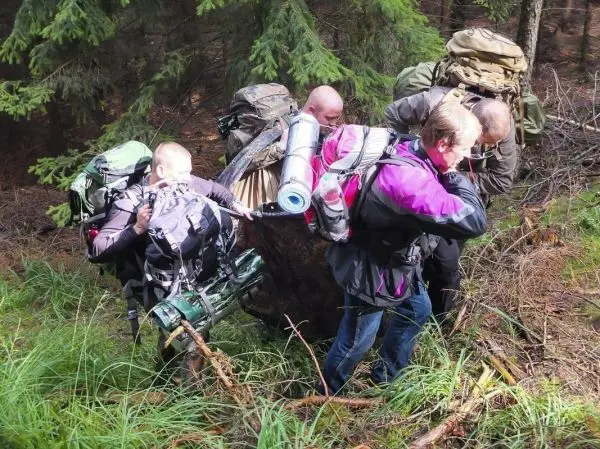 Gruppierung von Personen mit Rucksäcken über unebenes Gelände in einem Wald