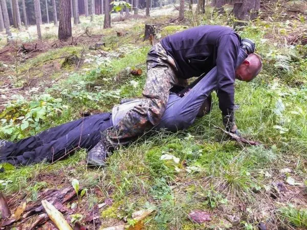 Kämpfer fixiert Gegner im Gras zwischen Bäumen