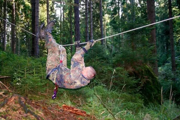 Person schwingt an einer Seilüberquerung durch den Wald beim Survival Training