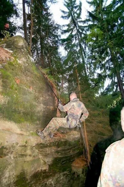Person seilt an einer Felswand ab im Wald beim Überlebenstraining