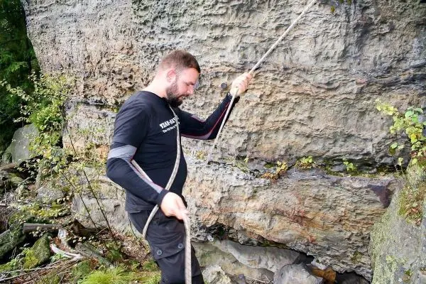 Person sichert Seil an Felswand beim Klettern