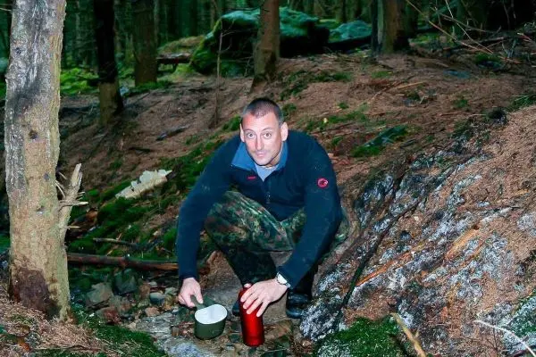 Person sitzt am Boden und hält einen Kochtopf in der Hand