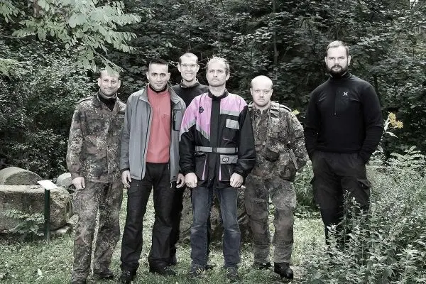 Sechs Personen stehen in einer Gruppe im Wald