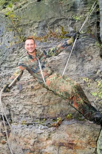 Seilquerung an einer Felswand mit gesichertem Seil und Handschuhen