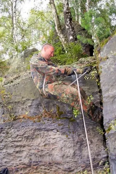 Seilquerung an einer steilen Felswand mit einem Seil in der Hand
