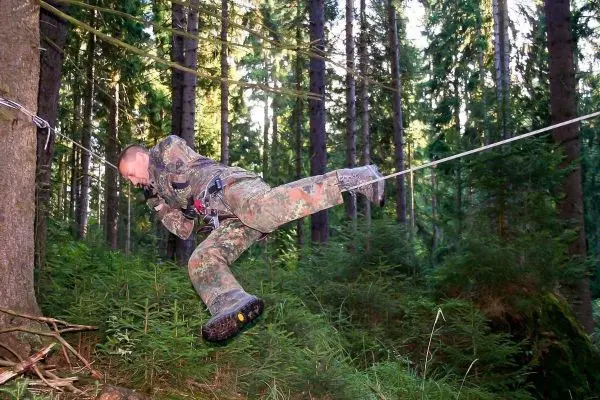 Selbstgebaute Seilquerung wird von einer Person in militärischer Ausrüstung überquert