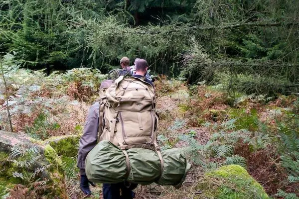 Wanderer trägt große Rucksackausrüstung auf schmalem Waldweg