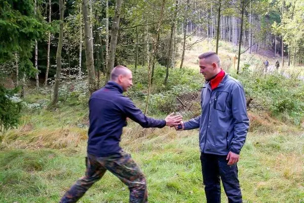 Zwei Personen führen einen Handschlag in einer Waldlandschaft durch