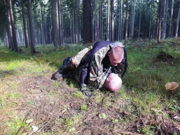 Zwei Personen im Wald, eine Person hält die andere am Boden