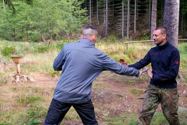 Zwei Personen üben eine Selbstverteidigungstechnik im Wald