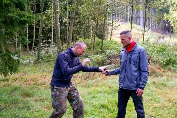 Zwei Personen üben eine Technik zur Handbefreiung im Wald