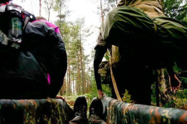 Zwei Personen ziehen eine improvisierte Trage durch den Wald