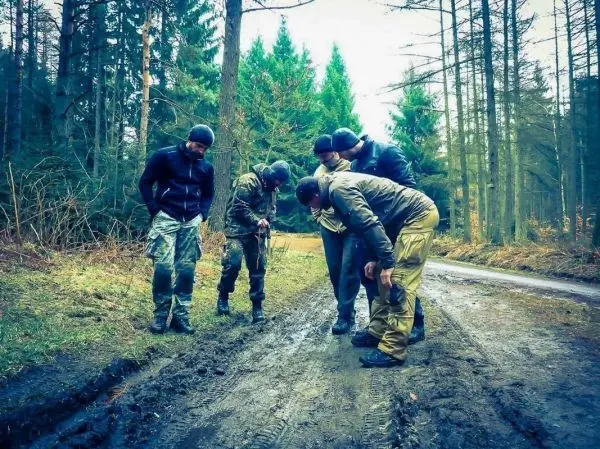Fünf Personen beugen sich über den Boden auf einem Waldweg