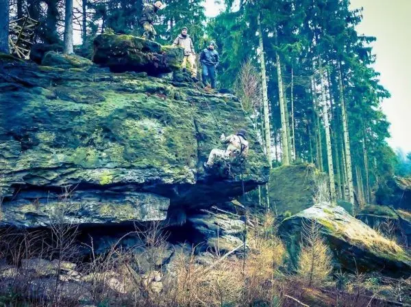 Kletterer nutzt Felsvorsprung, während andere beobachten und sichern