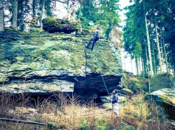 Kletterer sichert sich mit Seil an Felswand, während andere beobachten