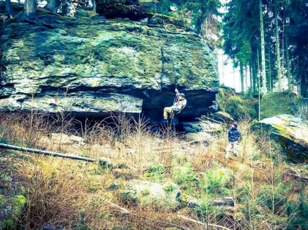 Person klettert an einem Felsen, während eine andere Person beobachtet