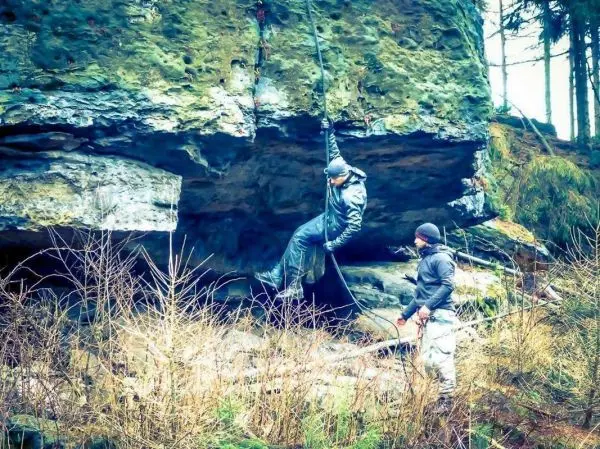 Seilquerung unter einem Felsen, eine Person hängt am Seil, eine andere beobachtet