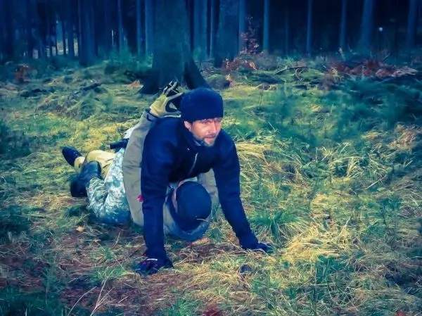 Zwei Personen in taktischer Kleidung üben eine Bodentechnik im Wald