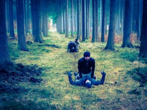 Zwei Personen üben eine Technik auf dem Boden in einem Waldgebiet