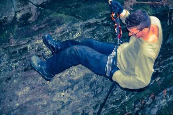 Abseilen an einer Felswand mit Sicherungsgerät und Karabiner