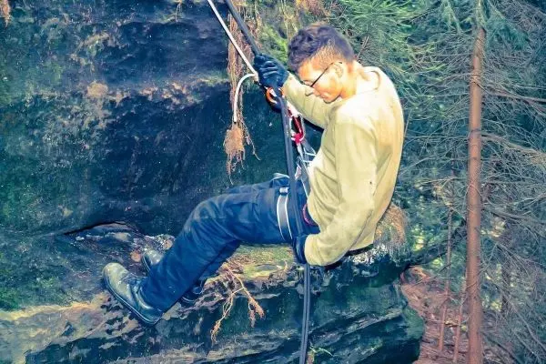 Abseilen an einer Felswand mit Sicherungsseil und Karabiner