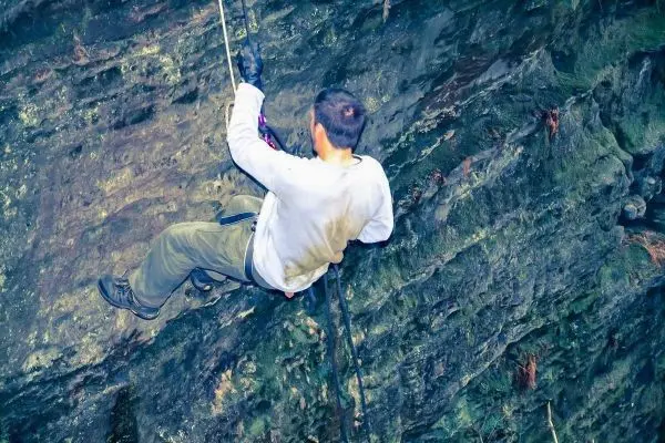 Abseilen an einer steilen Felswand mit Sicherungsseil und Kletterausrüstung