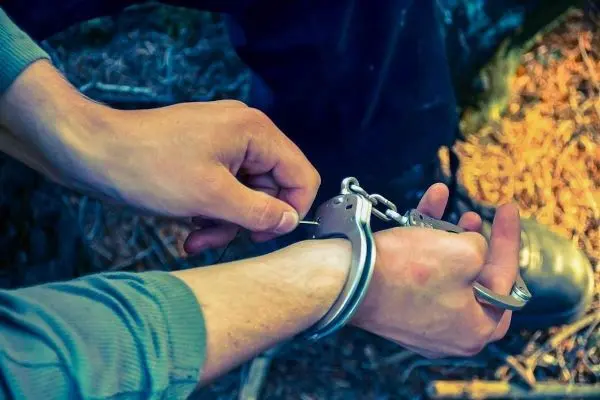 Hände legen Handfesseln an ein Handgelenk an