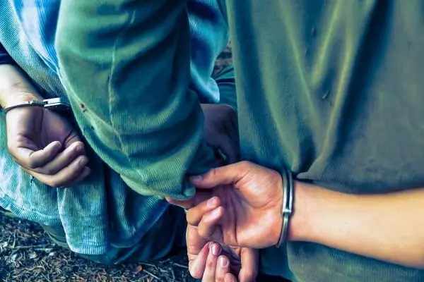 Hände mit Handschellen greifen sich gegenseitig