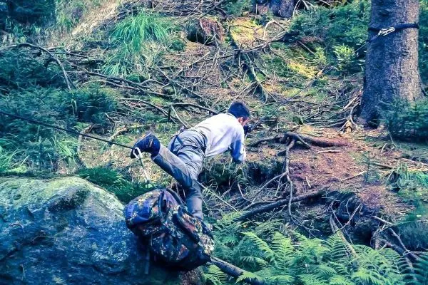 Junge überquert einen Stein mit einem Rucksack auf dem Rücken