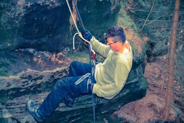 Kletterer nutzt Seil und Karabiner zur Abseilung an einer Felswand