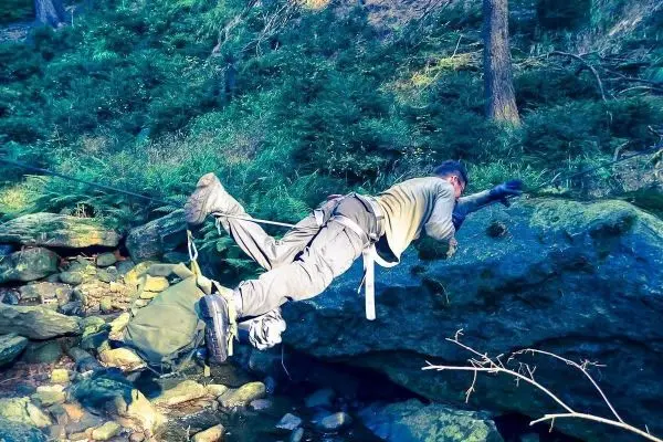 Mann überquert einen Fluss mit einer selbstgebauten Seilquerung
