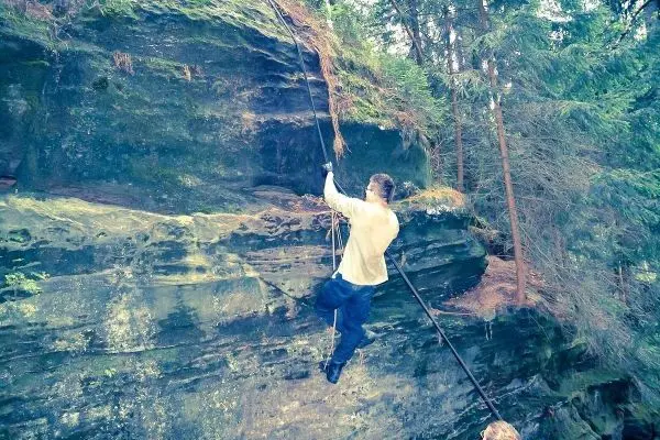 Person klettert an einer Felswand mit Seilhilfe
