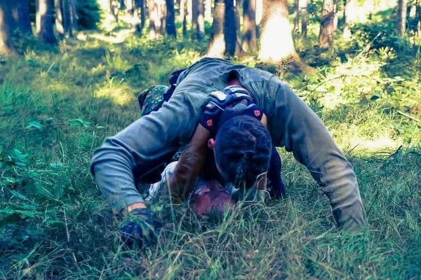 Person liegt auf dem Boden und übt eine Technik im Gras