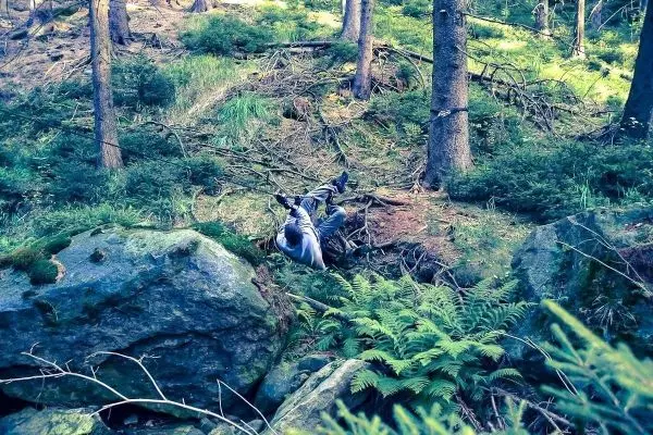 Person liegt auf dem Boden zwischen Steinen und Pflanzen im Wald