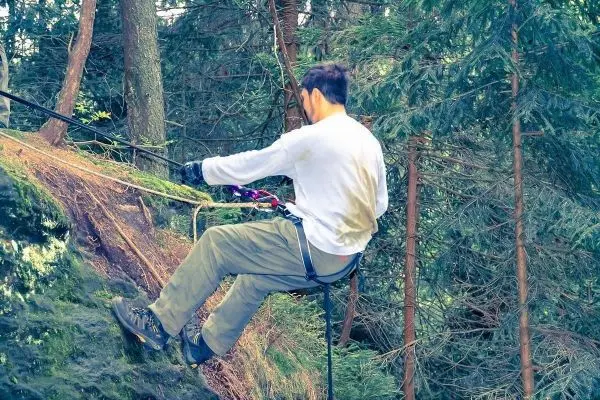 Person seilt an einer Felswand im Wald ab