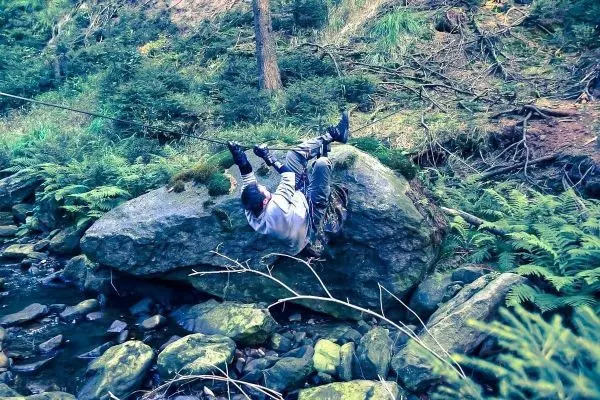 Seilquerung über einen großen Stein in einem bewaldeten Gebiet