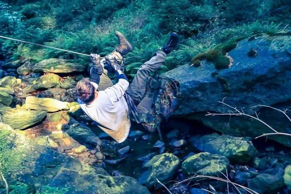 Seilquerung über einen kleinen Bach mit Felsen im Hintergrund