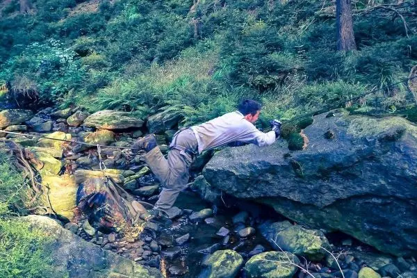 Selbstgebaute Seilquerung über einen kleinen Bach mit Felsen und Pflanzen im Hintergrund