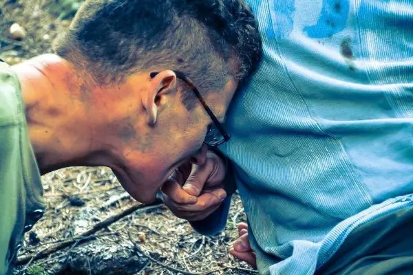 Zwei Personen interagieren am Boden, eine Person beugt sich über die andere