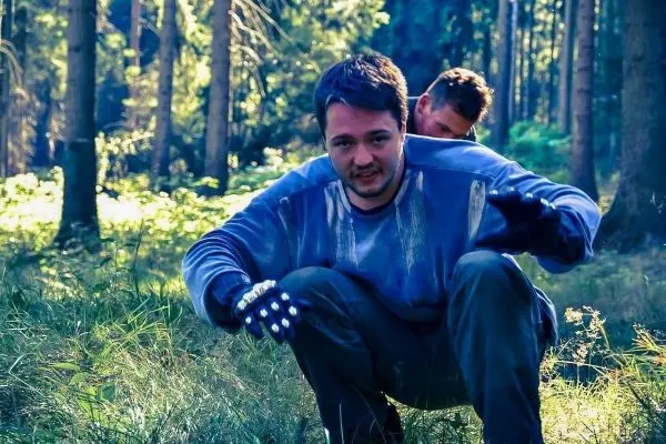 Zwei Personen knien im Wald und scheinen sich auf den Boden zu konzentrieren