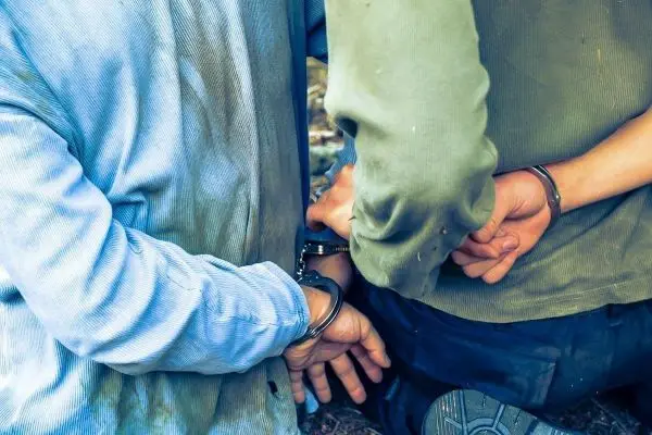 Zwei Personen mit Handschellen stehen Rücken an Rücken