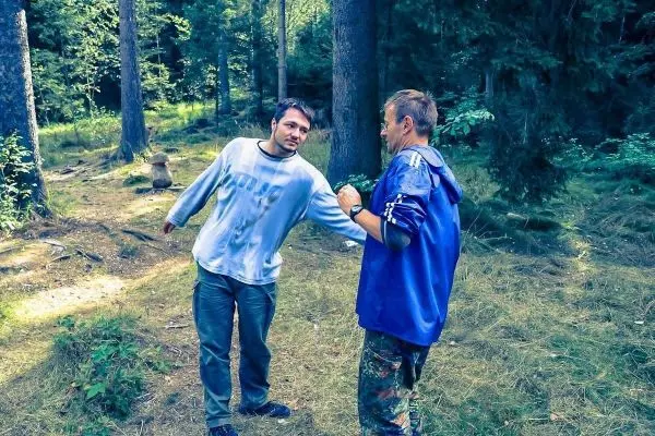 Zwei Personen stehen im Wald und unterhalten sich