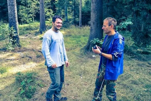 Zwei Personen stehen im Wald und unterhalten sich